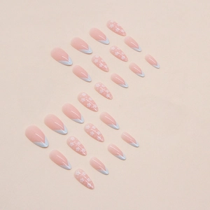 Long almond press-on nails in nude pink with white French tips and small flower patterns
