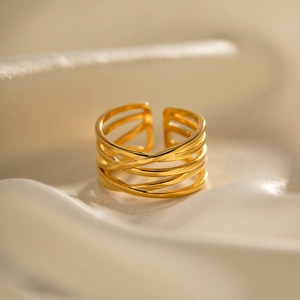 Macro shot of gold plated multi-layer cross ring displayed on elegant beige silk fabric