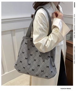 Detail of grey quilted tote bag featuring black bow patterns and durable shoulder strap