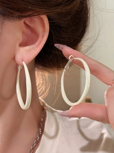 Close-up of creamy white enamel hoop earring worn to show the elegant size and soft finish