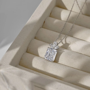 Macro shot of rectangular clear gemstone pendant with silver bow detail on velvet display