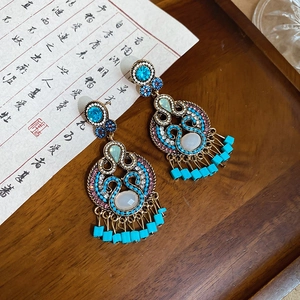 Detailed macro shot of vintage gold earrings with turquoise stone and hollow leaf tassels