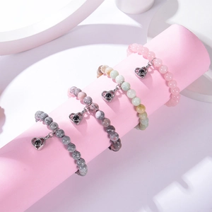 Détail de bracelets en perles de pierre zébrée rose avec pendentifs en cœur sur support