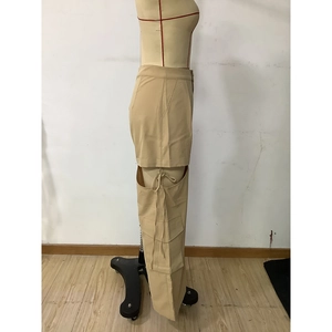 Detail of khaki cargo pants featuring unique hollow-out cutouts and lace-up leg design