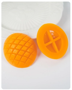 Macro shot of mango-shaped silicone scrub brush with cross-ribbed back on white ceramic plate