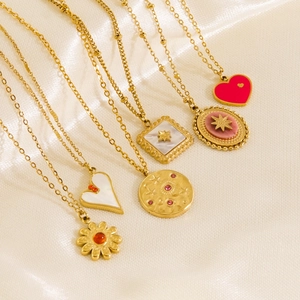 Gold plated necklaces with heart and flower pendants on champagne silk background