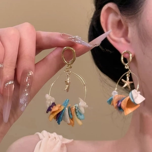 Gold round earrings with starfish charms and colorful shell fringe tassels on model