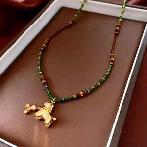Macro view of beaded necklace with gold dog pendant and green tiger eye beads