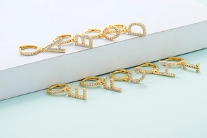 Close-up of golden alphabet earrings A to I with sparkling zircon stones in a macro view