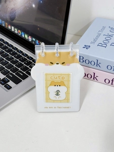 Close-up of a white hamster-themed photo card binder on a desktop with clear PVC pocket