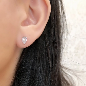 Close-up of a pear-cut white zircon stud earring in silver on a woman's earlobe