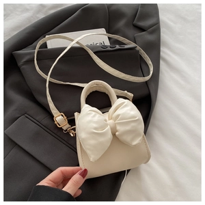Detailed view of cream PU leather crossbody bag featuring a large decorative bow