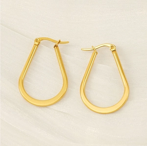 Polished gold U-shaped hoop earrings on white silk fabric with a shiny mirror finish