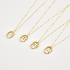 Macro view of gold S925 silver alphabet pendants B G M A with sparkling zircons