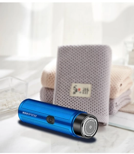 Detail view of a portable blue electric shaver with metal mesh cover and power button