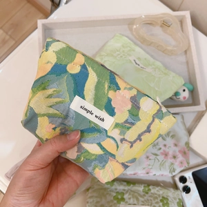 Close-up of green leaf jacquard fabric mini pouch with simple wish label and zipper