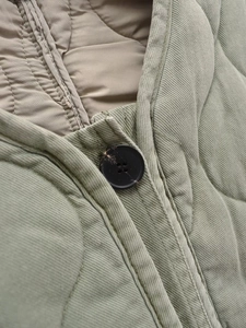 Détail d'une veste matelassée vert militaire avec boutons noirs et coutures précises