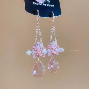 Close-up of vintage-style earrings featuring pear-cut pink stones and floral zircon accents