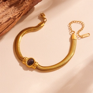 Detail of gold snake chain bracelet with oval purple gemstone and stainless steel clasp