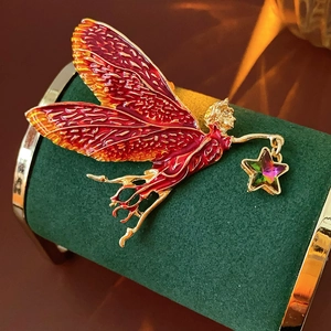 Macro shot of vintage fairy brooch with red enamel wings and gold star pendant charm