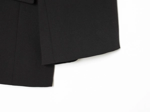 Vue macro montrant la texture du tissu sergé noir et les détails de couture de qualité