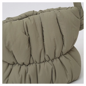 Detailed close-up of quilted nylon fabric on olive green padded down shoulder bag