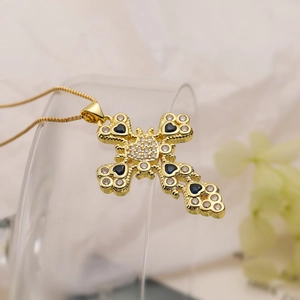 Detailed view of a gold-plated cross pendant featuring white and blue inset gemstones