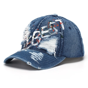 Close-up of distressed denim baseball cap with VIBES embroidery and paint splatters