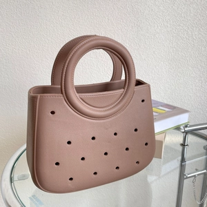 Sac de plage marron en EVA avec perforations et poignée ronde sur table en verre