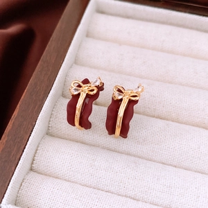 Detail of vintage 18k gold plated bow earrings with burgundy enamel and rhinestones