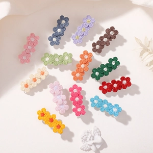 Flat lay of thirteen colorful embroidered floral hair clips in various vibrant pastel shades