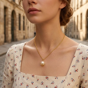 Elegant gold necklace with a large round white pearl pendant on a delicate woven chain
