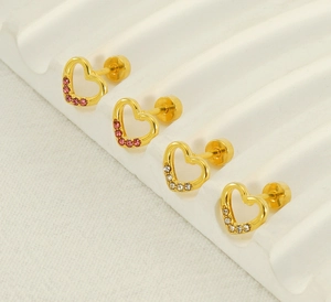 Macro detail of heart-shaped gold earrings with pink and white rhinestones and screw backs