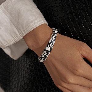 Close-up of black and white woven zebra pattern cuff bracelet on a woman wrist