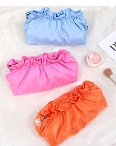Tre borse da trucco a pieghe in blu, rosa e arancione con eleganti tiri zip in perla