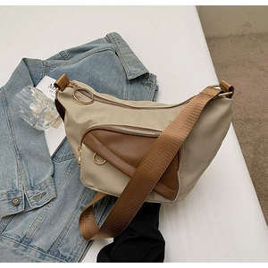 Detail of khaki and brown canvas crossbody bag with metal zippers and wide shoulder strap