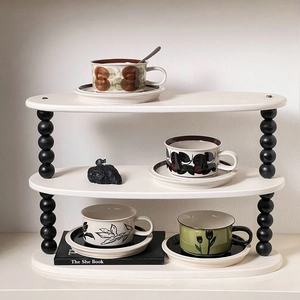 Three-tier white wooden shelf with decorative black beaded legs and oval shelves