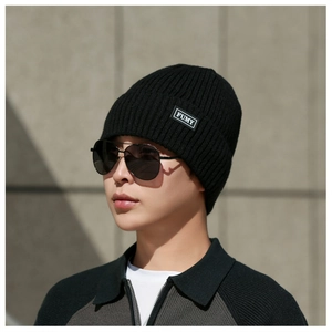 Detail of black ribbed knit beanie featuring a branded textile label and thick fabric