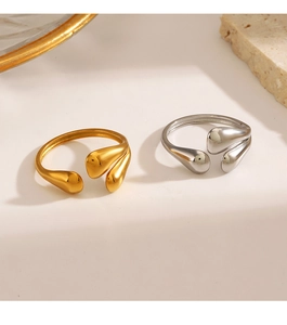 Close-up of minimalist gold and silver teardrop open rings on a stone surface