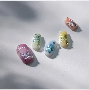 Macro shot of handmade press-on nails featuring 3D aurora butterflies and silver accents
