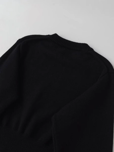 Detail of ribbed knit cuffs and neckline on black crewneck long sleeve sweater