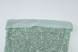 Close-up detail of mint green sequins and fabric edging on a slim fit evening dress