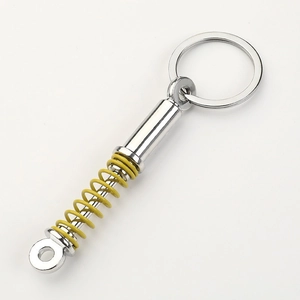 Car shock absorber keychain with yellow coil spring and polished silver alloy body