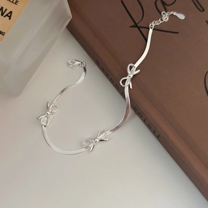 Élégant bracelet chaîne serpent en argent S925 avec nœuds posé sur un livre ancien