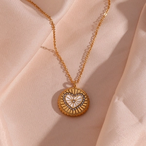 Détail macro d'un pendentif coeur doré sur un luxueux tissu de soie couleur champagne