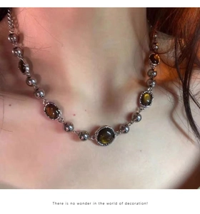 Detail of silver chain necklace with amber oval crystals worn on model neck