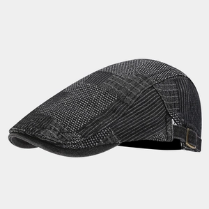 Close-up of vintage denim flat cap with grey patchwork textures and metal buckle