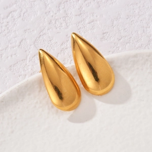 Macro shot of minimalist 18K gold plated teardrop earrings on white ceramic surface