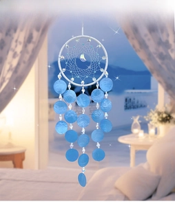 Close-up of handmade white dreamcatcher with blue shell slices and crystal beads
