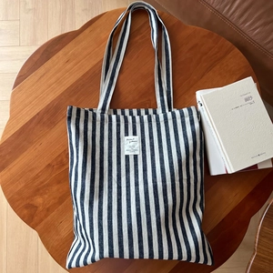 Détail d'un sac cabas en toile rayée avec étiquette tissée sur une table en bois